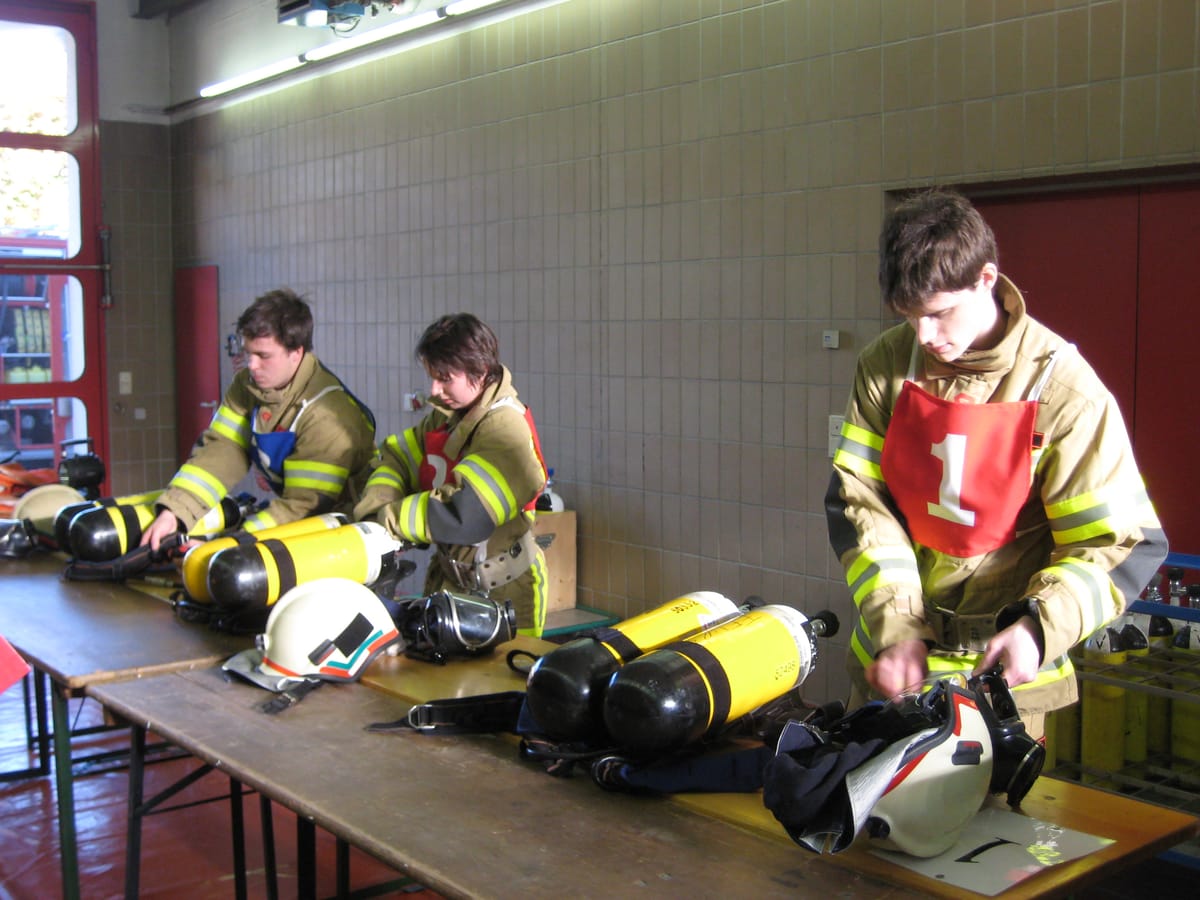 Eine Feuerwehrfrau und zwei Feuerwehrmänner mit Atemschutzgeräten