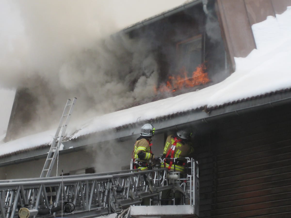 Feuerwehrmitglieder öffnen das Vordach mittels Drehleiter